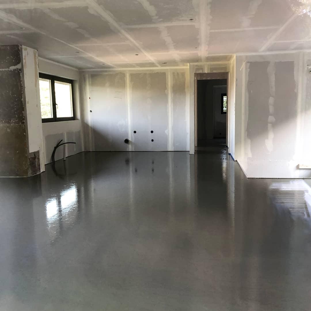 A large room with a freshly levelled grey floor