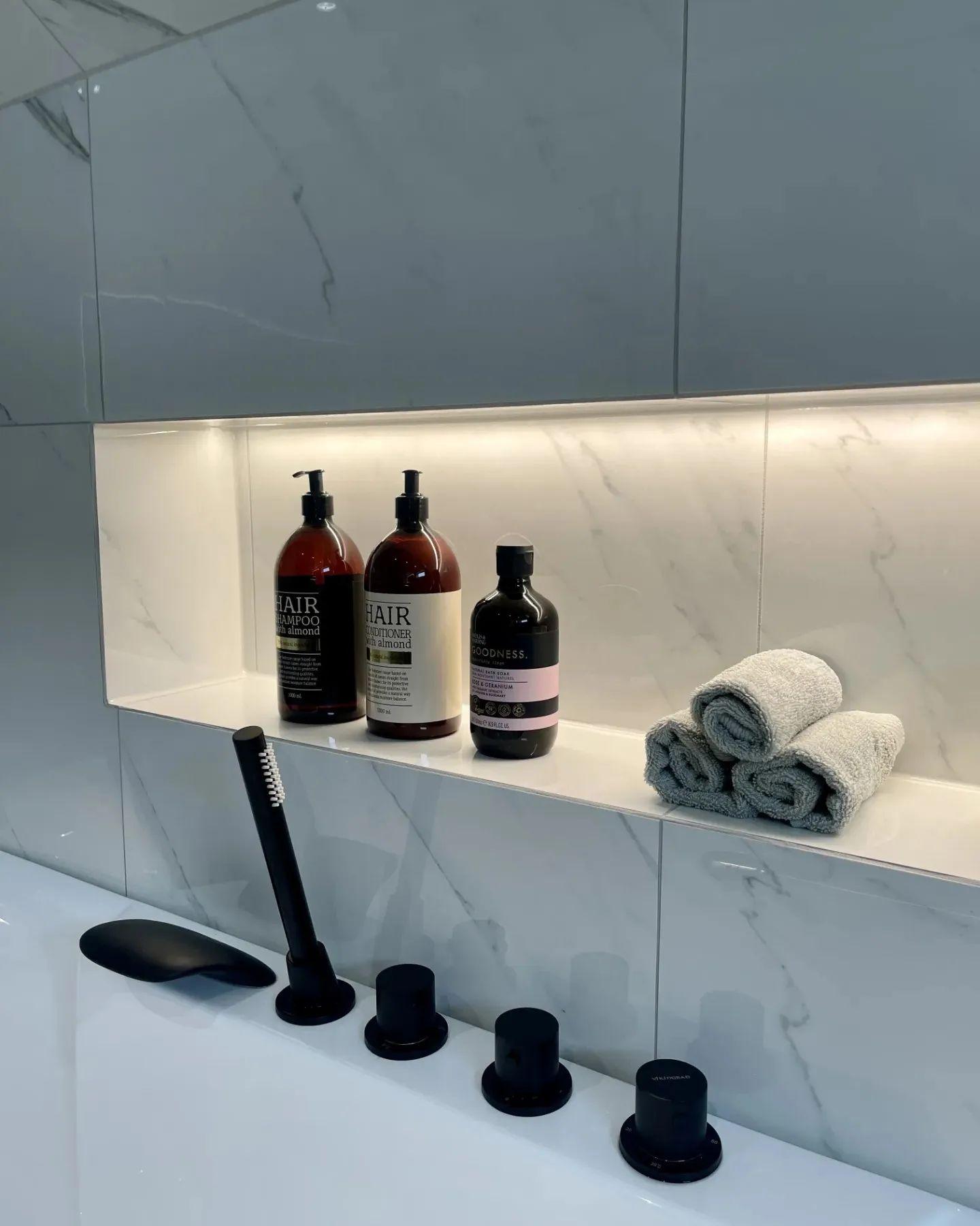 A lit niche tiled into a bathroom wall