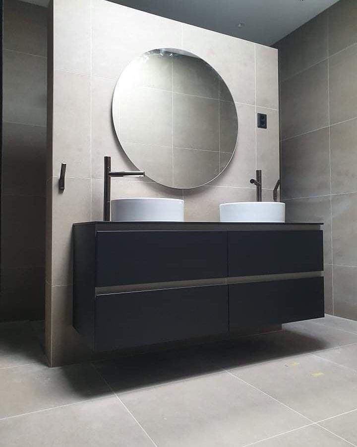 A black double vanity with round mirrors