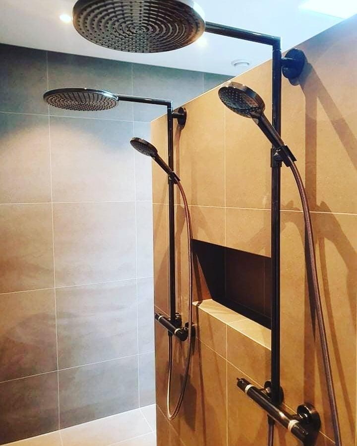 Black shower fittings against a wood-look wall