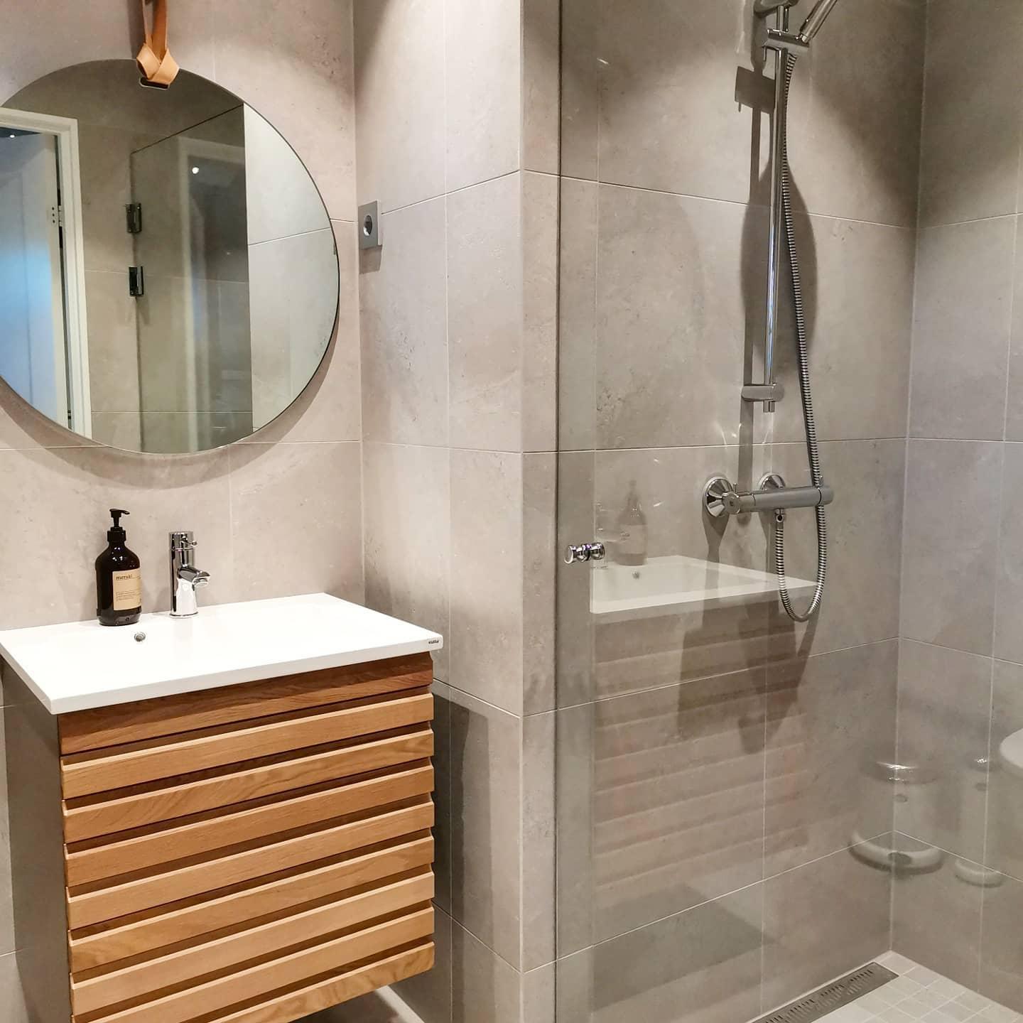 A small bathroom with a wooden vanity and a shower