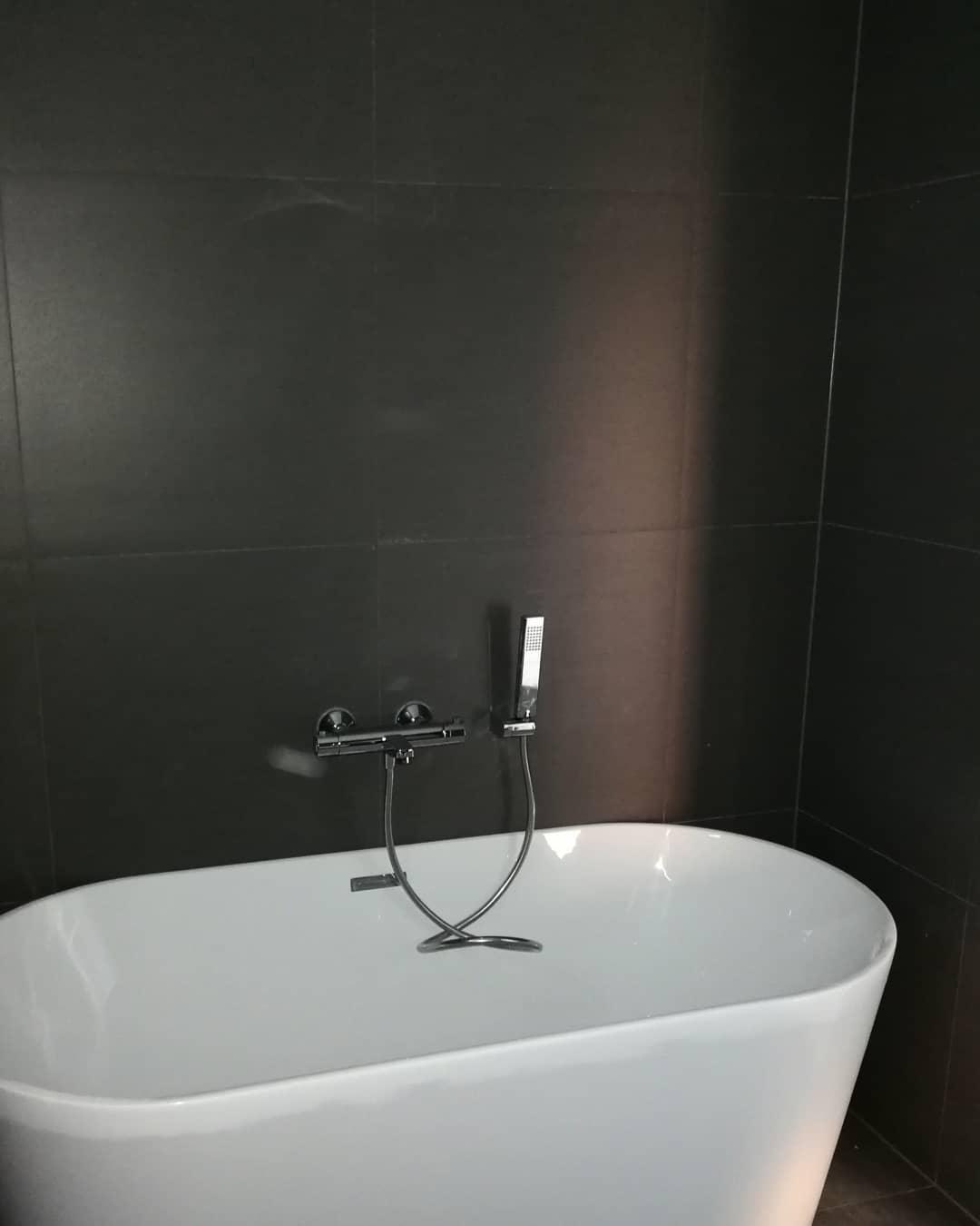 A freestanding bath in a bathroom with dark walls
